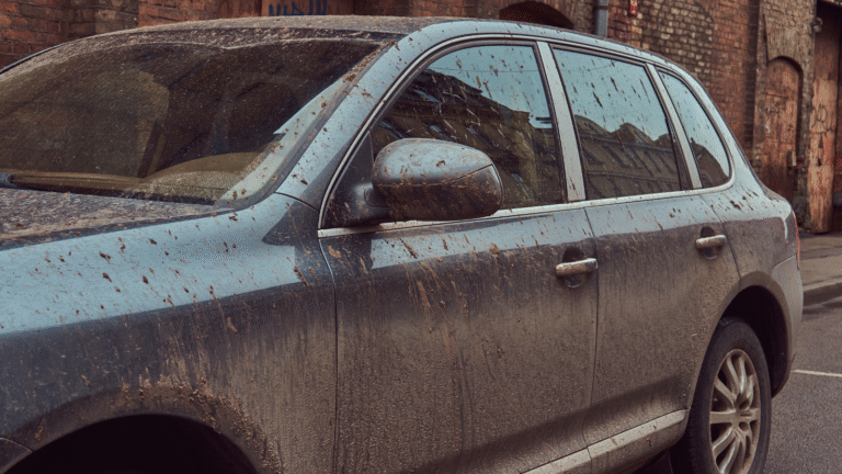 Dirty car parked on city street.