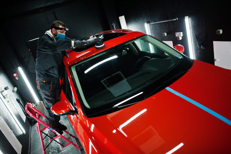 Car detailing concept. Man in face mask with orbital polisher in
