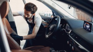 Man cleaning car interior meticulously.