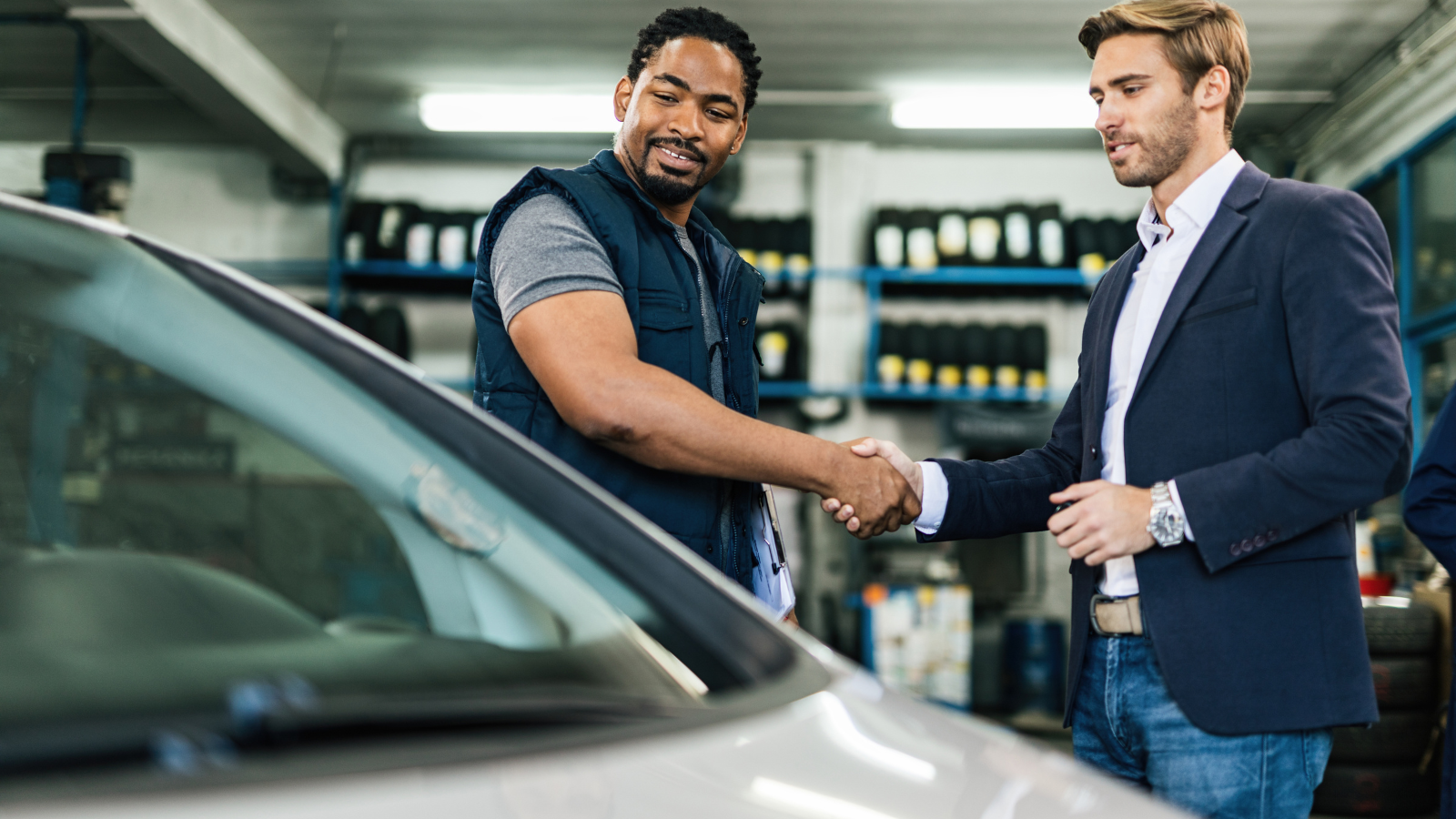 Two men shaking hands in garage.